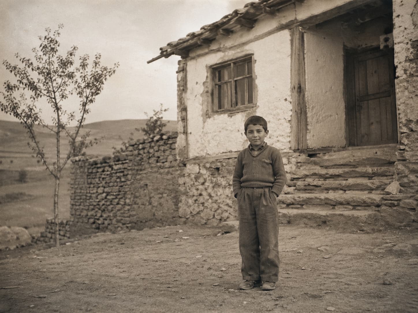 Junge in den 1950ern vor einem alten anatolischen Dorfhaus